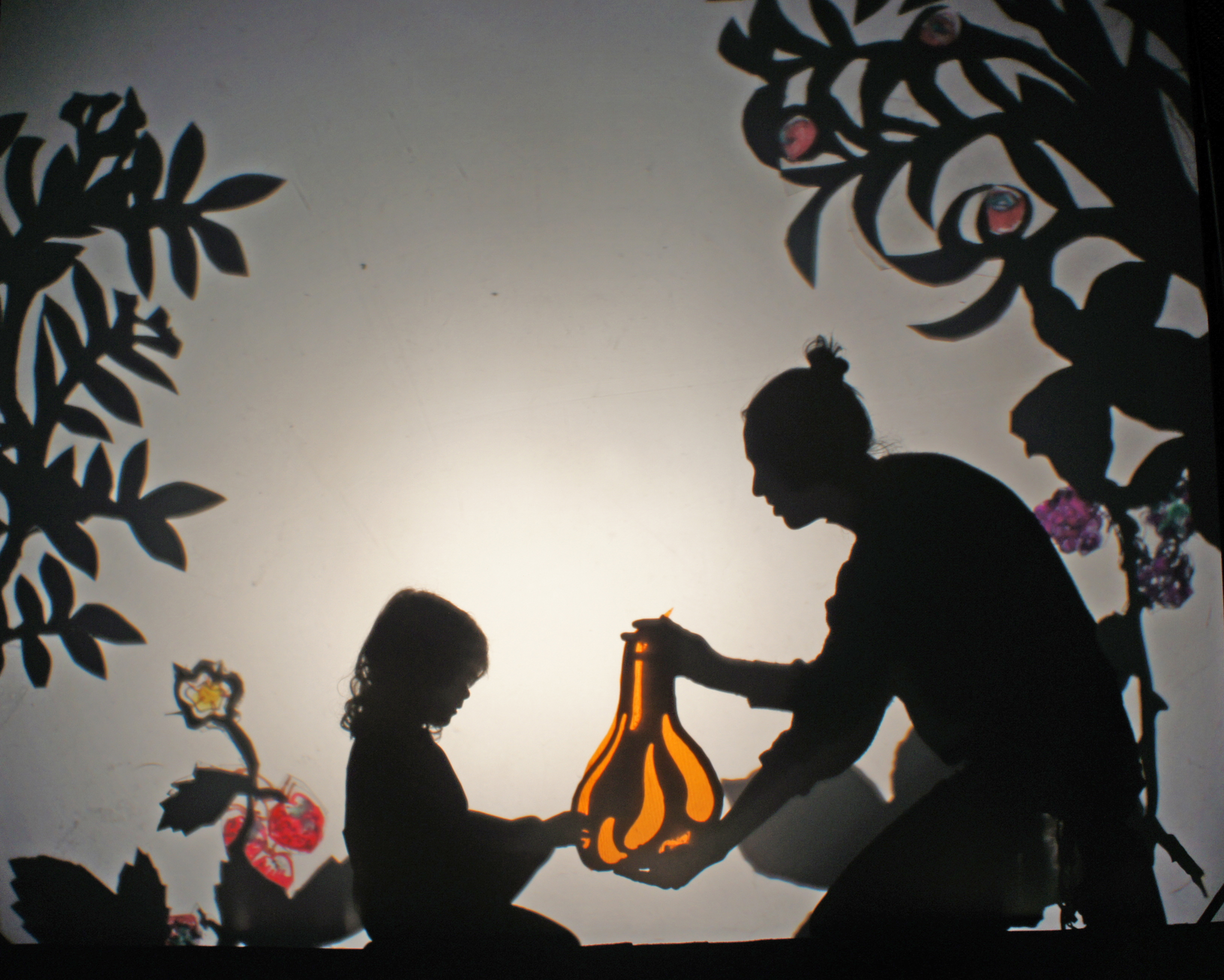 shadow theatre image of parent and child holding a squash in a forest garden